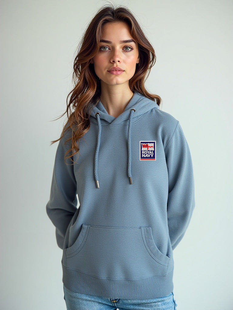 Female model wearing a stone blue hoodie with the Royal Navy badge embroidered on the left chest, posed casually against a neutral backdrop.