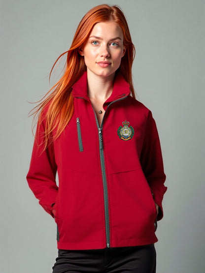 “Red-haired female model wearing a women’s Royal Engineers red softshell jacket with stand-up collar, full-length front zipper, chest zip pocket, side hand pockets and Royal Engineers Logo embroidered on left breast.”