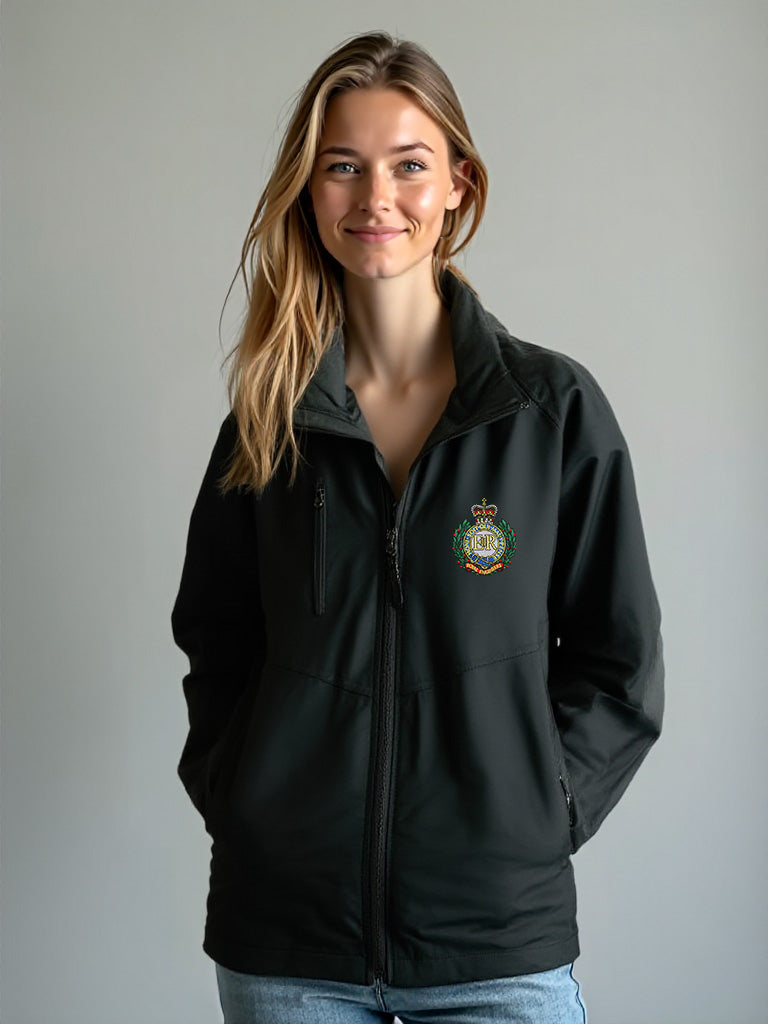 “Smiling female model wearing a women’s Royal Engineers black softshell jacket with stand-up collar, full-length front zipper, chest zip pocket, side hand pockets and Royal Engineers Logo embroidered on left breast.”