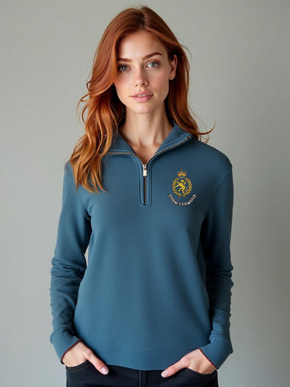 Female model wearing a storm blue WRAC half-zip sweatshirt with the WRAC emblem stitched on the left chest, standing in a neutral setting.